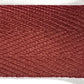 Close-up of a textured red-brown fabric strip on a white background