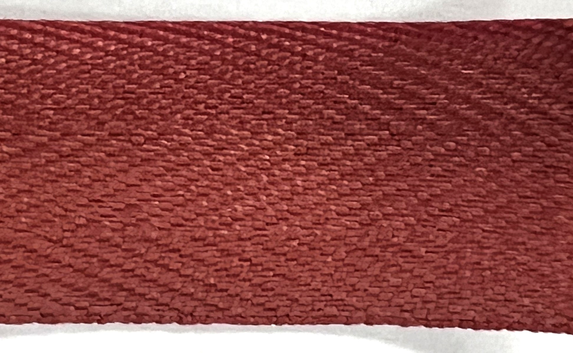 Close-up of a textured red-brown fabric strip on a white background