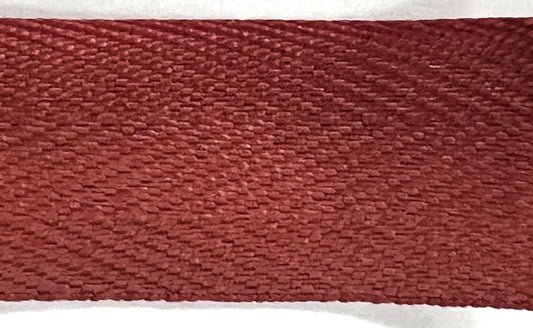 Close-up of a textured red-brown fabric strip on a white background